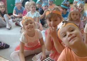 Dzieci z grupy Liski i Motylki i Biedronki siedzą na dywanie.