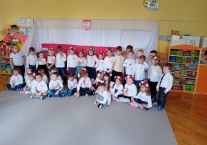 Dzieci stoją w kole, ubrane na galowo, śpiewają hymn Polski
