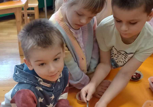 Dzieci stoją dookoła stołów, komponując swoje napoje herbaciane.