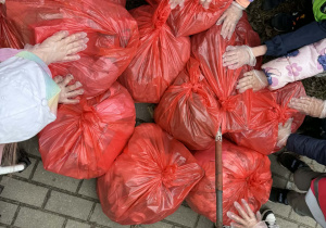 Dzieci stoją dookoła zabranych worków śmieci.