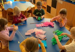Biblioterapia w grupie I. Dzieci owijają długie patyczki kolorową bibułą.