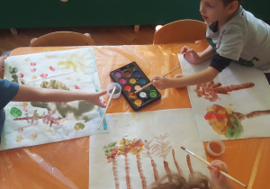 Plastykoterapia w grupie 4. Na zdjęciu widzimy dzieci malujące farbami akwarelowymi.