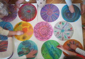 Plastykoterapia w grupie 3. Kropkowe dzieła sztuki. Dzieci suchymi pastelami ozdabiają kolorowe koła.