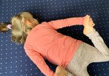 Terapia ręki. w grupie 1.Dziecko leży na brzuchu. Nogi ugięte w kolanach, dłońmi trzyma stopy.