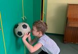 Terapia ręki w grupie 1. Dziecko w przysiadzie toczy piłkę po ścianie.