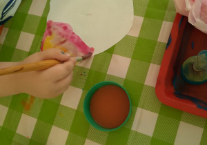 Plastykoterapia w grupie 4. Dziecko maluje farbami karton w kształcie liścia.