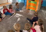 Teatroterapia w grupie 1. Dzieci siedzą przy drewnianym teatrzyku. Nauczycielka inscenizuje bajkę za pomocą kukiełek.