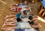 Zajęcia wg metody RR W. Sherborne w grupie 1. 9 dzieci leży na brzuchu obok siebie. jedno z dzieci przeczołguje się po nich.