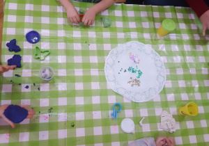 Plastykoterapia w grupie 4. Na zdjęciu widać dłonie dzieci, które robią toruńskie pierniczki z ciastoliny.