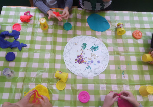 Plastykoterapia w grupie 4. Na zdjęciu widać dłonie dzieci, które robią toruńskie pierniczki z ciastoliny.
