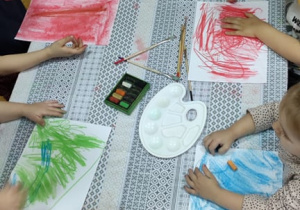 Plastykoterapia grupa 5. Grupa dzieci wykorzystując suche pastele koloruje białe kartki, odzwierciedlając "swoje smutki".
