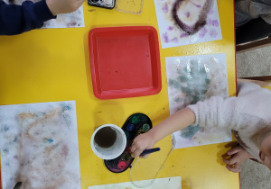 Plastykoterapia grupa 3. Na zdjęciu widać prace plastyczne dzieci wykonane farbami akwarelowymi, przedstawiające ich emocje.