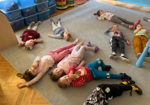 Dzieci leżą na dywanie. odtwarzają fragmenty opowiadania "Mój przyjaciel ze snu".