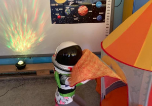 Teatroterapia w gr. 1. Zdjęcie przedstawia dziecko przebrane za kosmonautę. Wchodzi do namiotu imitującego rakietę.
