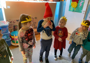 Teatroterapia grupa 1. Dzieci stoją w kole. Chłopcy w czapkach krasnoludków, dziewczynki w koronach. Przekazują sobie jabłko.