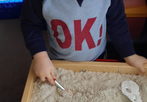 Terapia ręki grupa 2. Na zdjęciu widać chłopca bawiącego się piaskiem kinetycznym.
