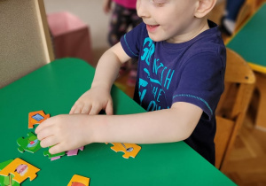 Grupa 5. Chłopiec układa kolorowe puzzle.