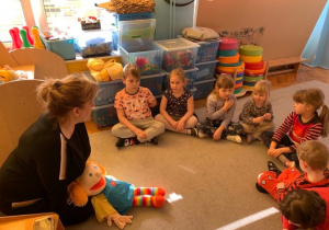 Biblioterapia w grupie 1. Nauczycielka z dziećmim siedzi na dywanie. za pomocą lalki inscenizuje treść opowiadania.