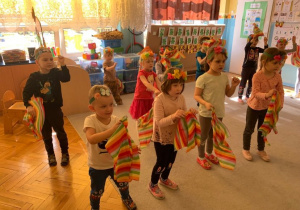 Choreoterapia w grupie 1. Dzieci w wiosennych opaskach na głowach odtwarzają układ choreograficzny - tańczą przy muzyce.