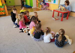 Teatroterapia grupa 5. Dzieci siedzą na dywanie, oglądając teatrzyk "Trzy Świnki".
