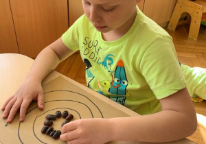 Gr. 1. Chłopiec układa fasolę na wzorze - okręgi.