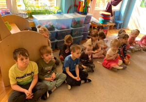 Biblioterapia w gr. 1. Dzieci siedzą na dywanie i słuchają opowiadania.
