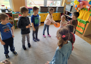 Teatroterapia grupa 5. Dzieci, stojąc w kółku, przekazują z rąk do rąk balonik.