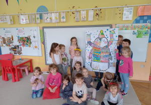 Plastykoterapia grupa 5. Grupa dzieci prezentuje wspólnie wykonany plakat pingwina, ułożony z puzzli, pomalowany farbami akwarelowymi.