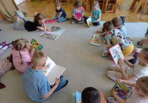 Biblioterapia grupa 5. Na zdjęciu widać grupę dzieci oglądających książki, o których indywidualnie opowiadały.