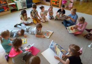 Biblioterapia grupa 5. Na zdjęciu widać grupę dzieci oglądających książki, o których indywidualnie opowiadały.