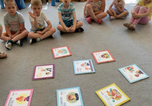 Gr. 1. Biblioterapia. Dzieci siedzą na dywanie. po środku rozłożone są książki dotyczące poznanych emocji.