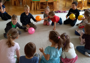 Teatroterapia. Grupa 5. Na zdjęciu widać dzieci siedzące na dywanie z kolorowymi piłkami, które pomagają spełniać marzenia.