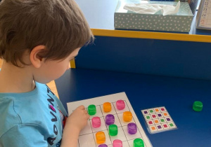 Terapia ręki gr. 1. Chłopiec układa kolorowe kostki według kodu.