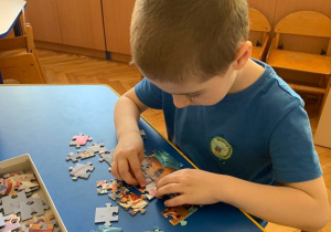 Gr. 1. Chłopiec układa puzzle.