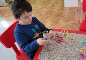 Grupa 5. Na zdjęciu widać chłopca, nakładającego kolorowe gumki na rolkę.