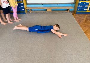 Grupa 1. Chłopiec ćwiczy na dywanie.