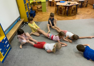 Grupa 1. Dzieci w parach przeciągają się ciągnąc kolegę leżącego na brzuchu za nogi.