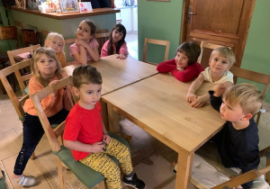 Dzieci siedzą przy stolikach, oglądając przedstawienie.