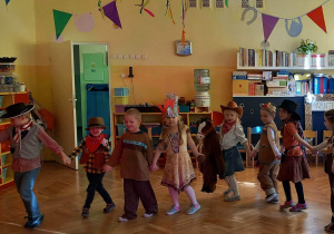 Dzieci w kółku tańczą na Balu Karnawałowym.