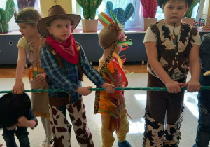 Dzieci na Balu Karnawałowym trzymają linę.