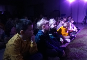 Dzieci siedzą w sali na spektaklu 'Pogaduchy z drzewem".