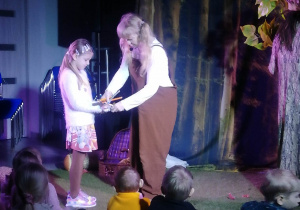Dziewczynka stoi na scenie z aktorką.