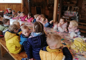 Dzieci siedzą w spiżarni konarzewskiej przy stole.