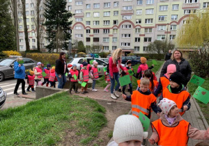 Dzieci niosąc zielone flagi, wraz z opiekunami idą do pobliskiego parku.
