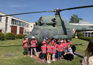 Grupa dzieci stojąca przed śmigłowcem w Wojskowych Zakładach Lotniczych.