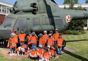 Grupa dzieci stojąca przed śmigłowcem w Wojskowych Zakładach Lotniczych.