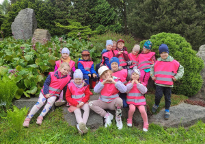 Grupa dzieci stoi wśród roślinności w Ogrodzie Botanicznym.