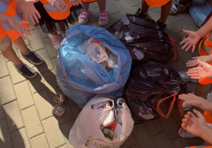 Dzieci pokazują zebrane przez siebie śmieci w workach.
