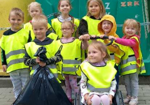 Dzieci stoją przy koszach ze śmieciami.
