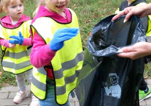 Dzieci w parku zbierają śmieci.